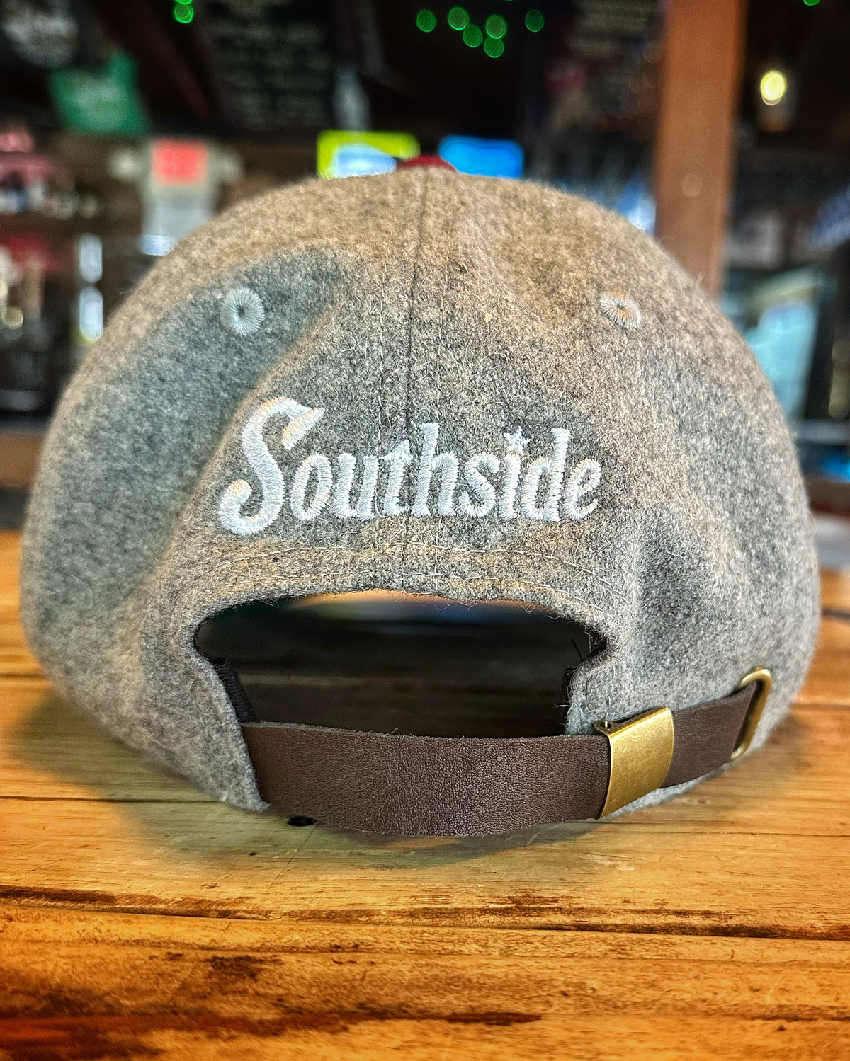 Southside Golf Co heritage golf hat back view with leather strap on wooden bar surface