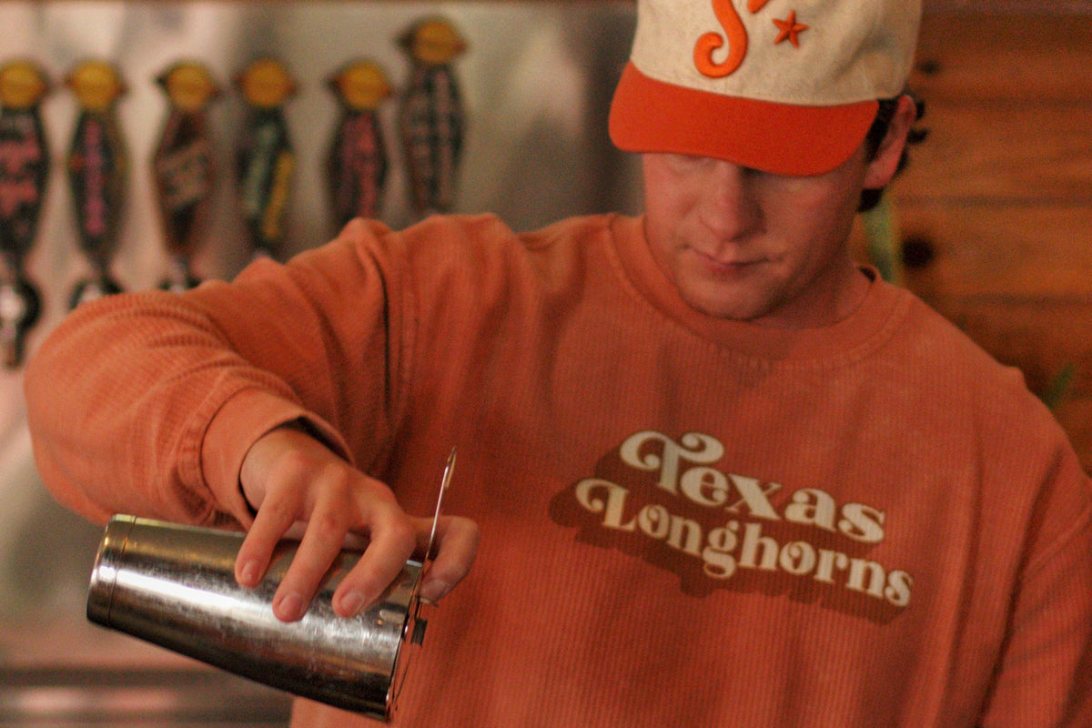 Man wearing Southside Golf Co heritage golf hat in casual Austin setting with orange sweatshirt