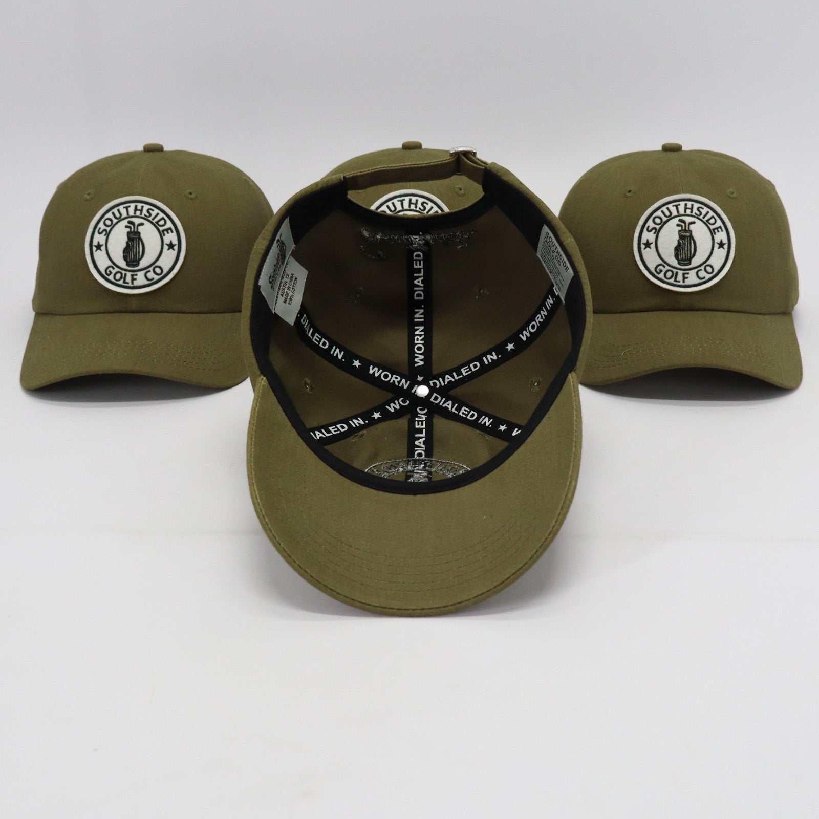 Multiple Southside Golf Co olive unstructured dad hats showing embroidered logo patch and ‘Worn In. Dialed In.’ interior taping on white background.