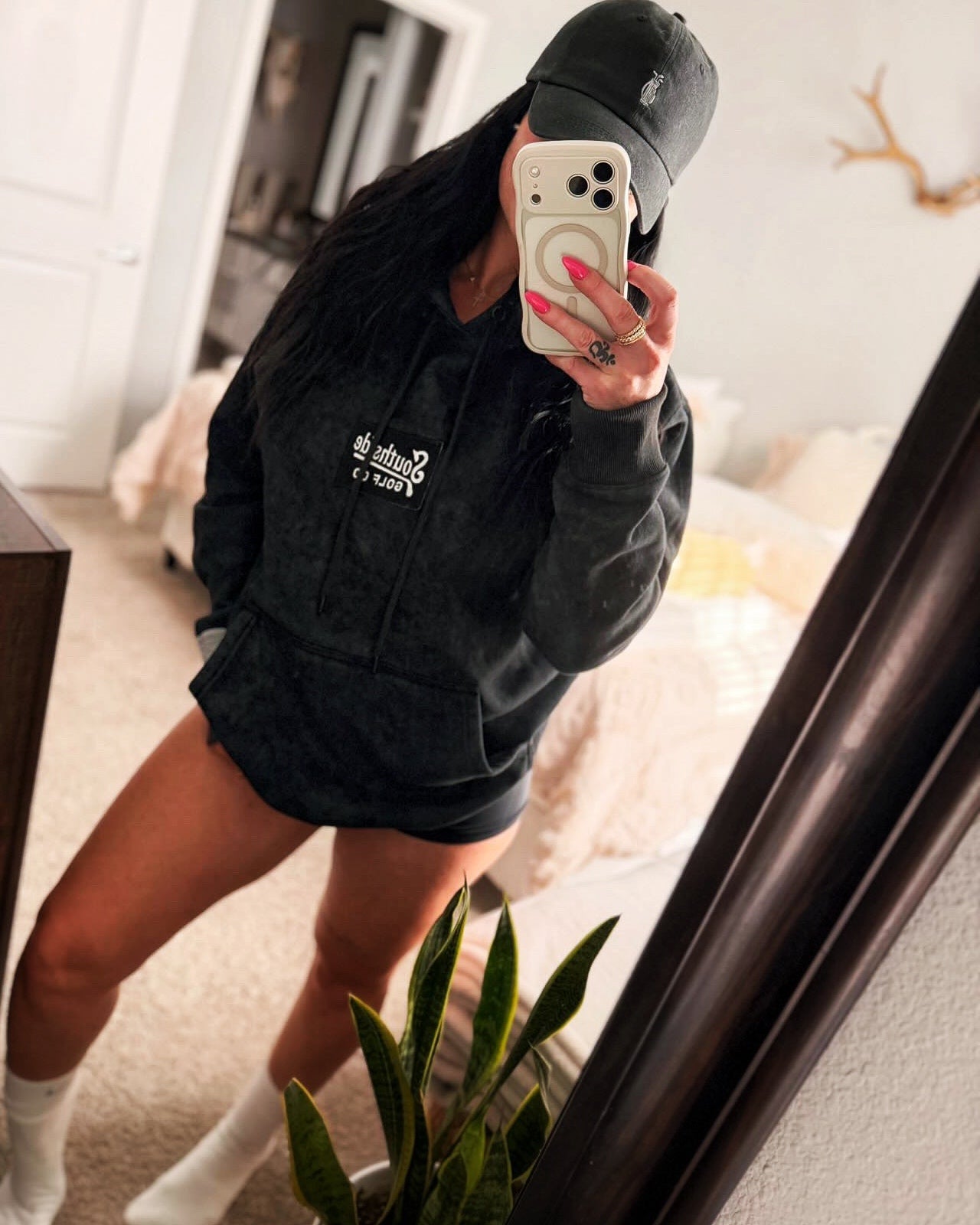 Model wearing a black Southside Golf Co. heavyweight hoodie with woven logo patch and a black Southside Golf Co. dad hat in a casual lifestyle setting.