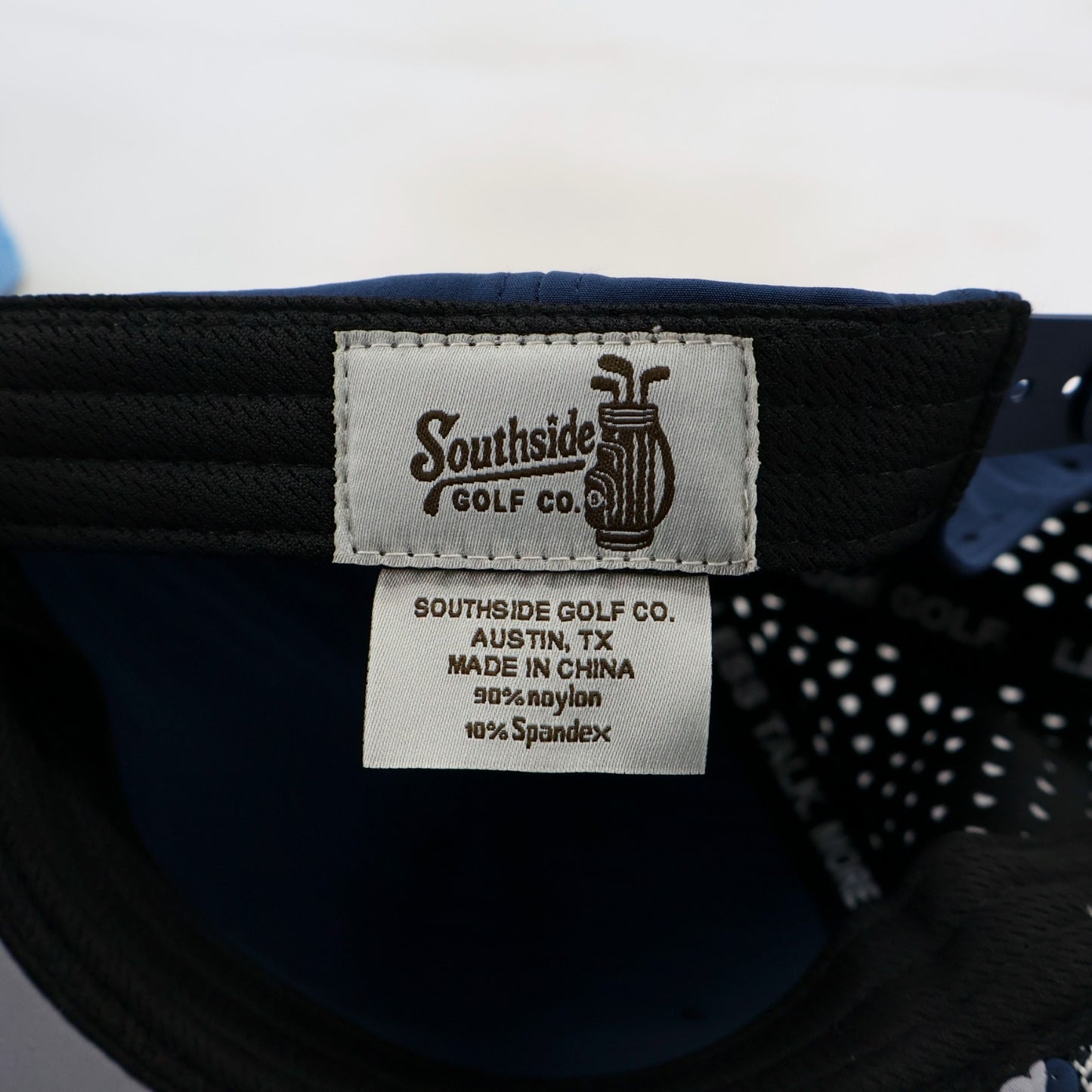 Close-up of a Southside Golf Co. label on a navy cap with white interior.