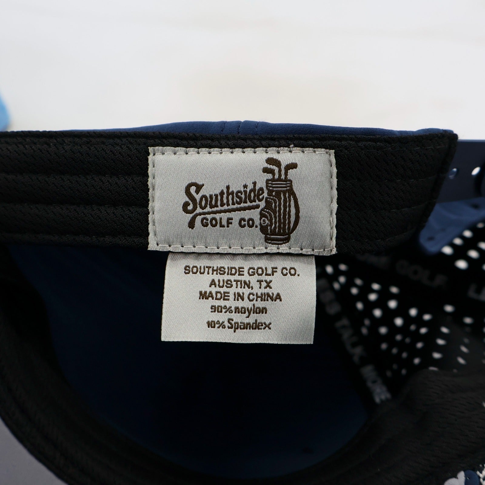 Close-up of a Southside Golf Co. label on a navy cap with white interior.