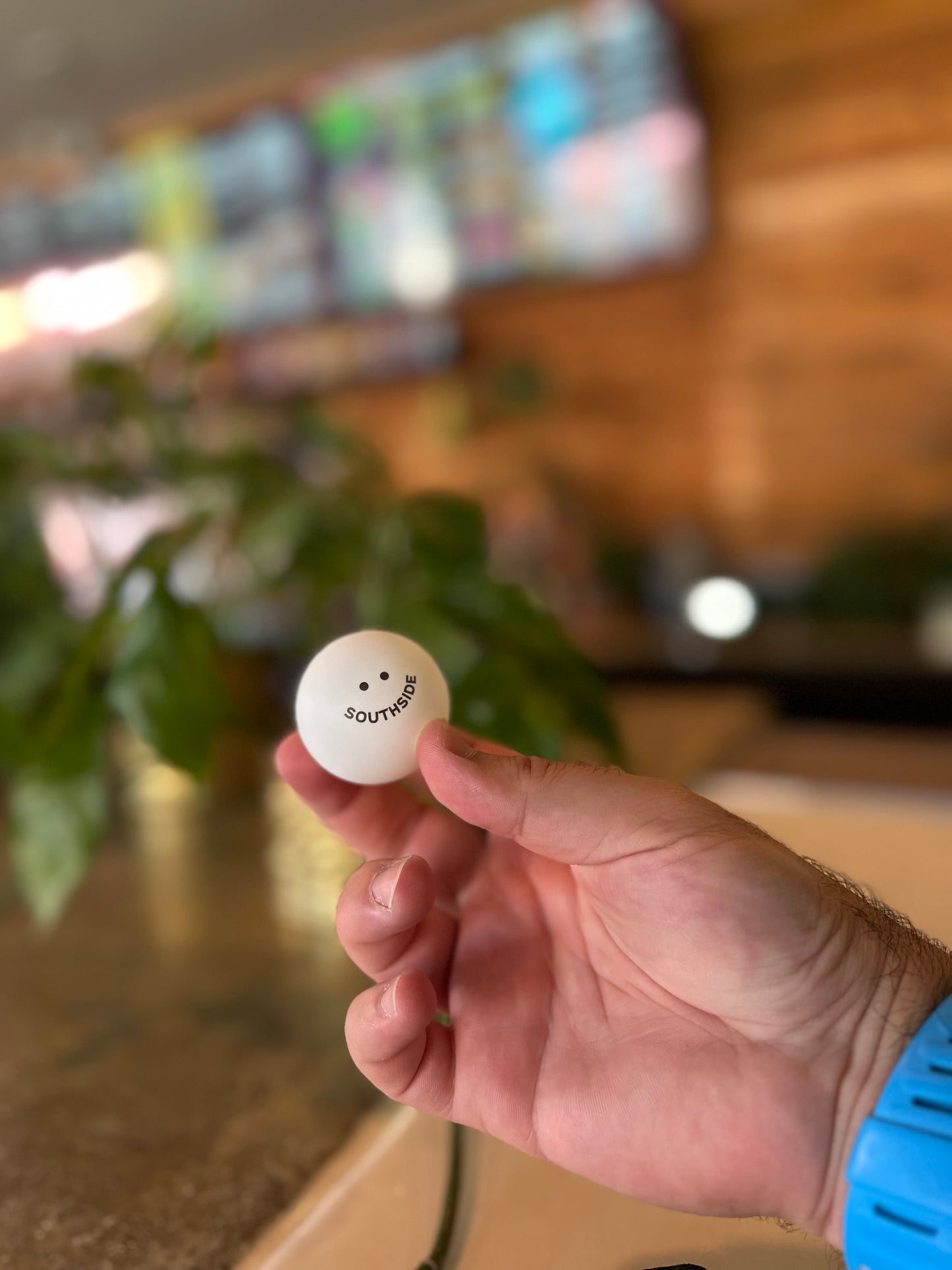 Hand holding Southside Golf Co branded white ping pong ball