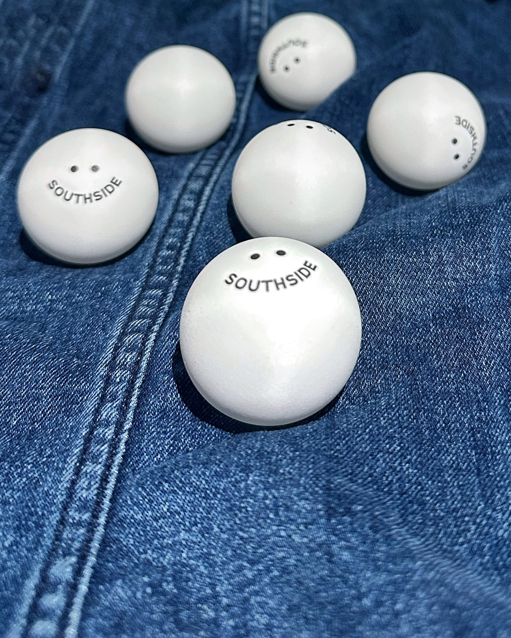 Southside Golf Co branded white ping pong balls on denim background.
